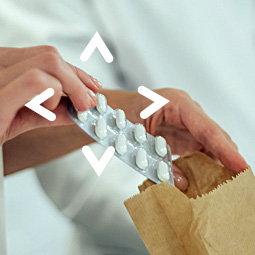 Closeup of a pharmacist inserting a pill packet into bag