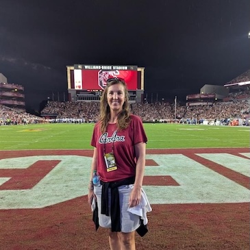 Dr. Amber Fallucca stands in the end zone of Williams-Brice Stadium with the jumbotron immediately over her head