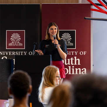 Student Body President Courtney Tkacs speaks in front of University of South Carolina banners during Imagine Carolina 2025