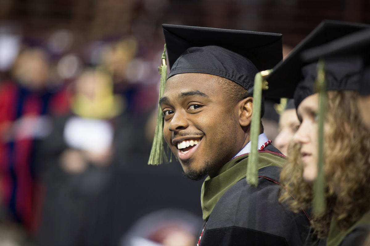a Carolina graduate smiles at a commencement ceremony