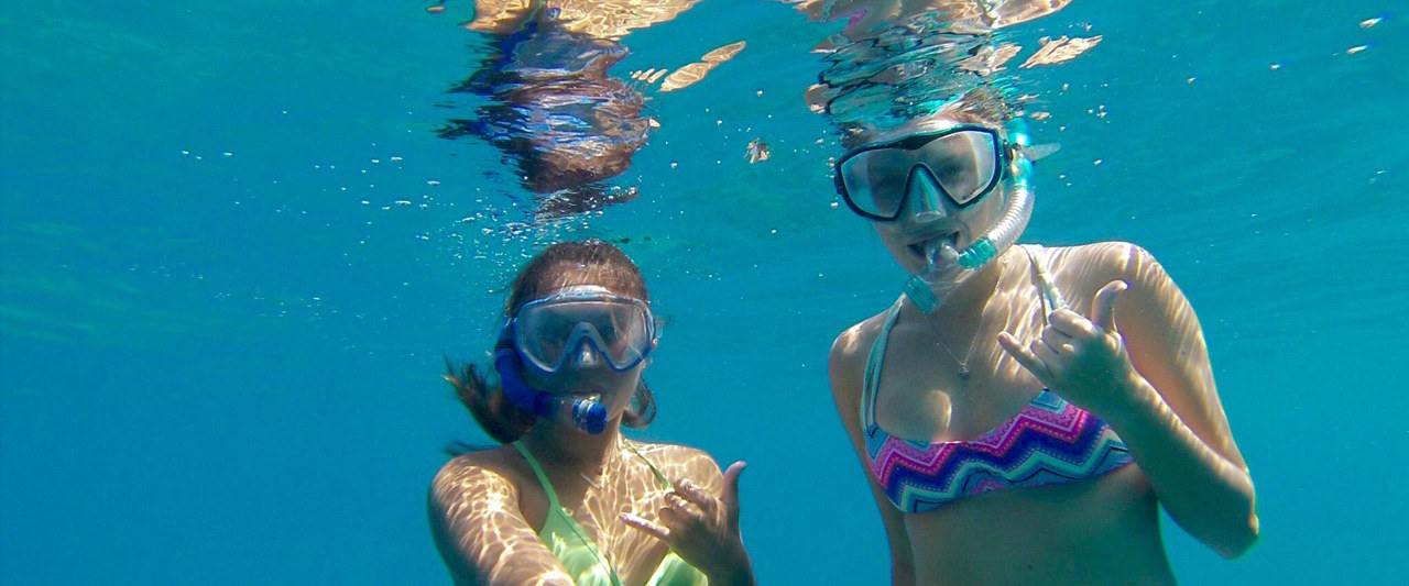Two students underwater snorkeling while holding their spurs up