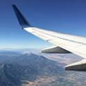 Airplane wing over a mountainous sky