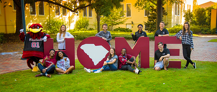 students and cocky posing in front of the letters HOME