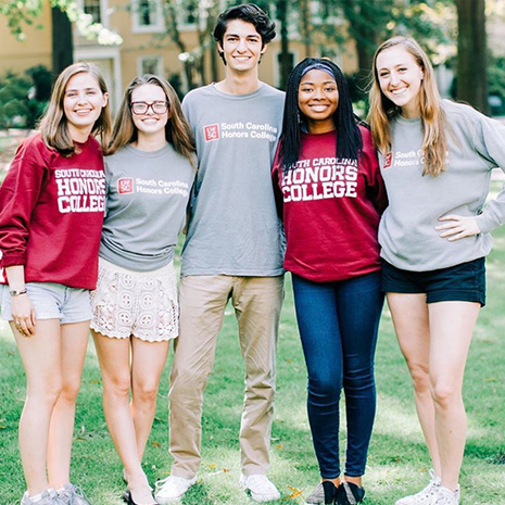 Group of honors college students standing on the horseshoe wearing honors college shirts and hats 