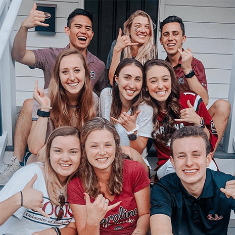 A group of students gathered on porch steps in garnet and black