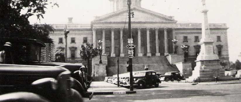 A 1940s view from across Gervais Street of the South Carolina State House in Columbia with cars parked in front of it