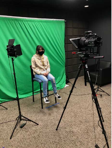 woman sitting on a chair in the video production studio surrounded by lights and camera