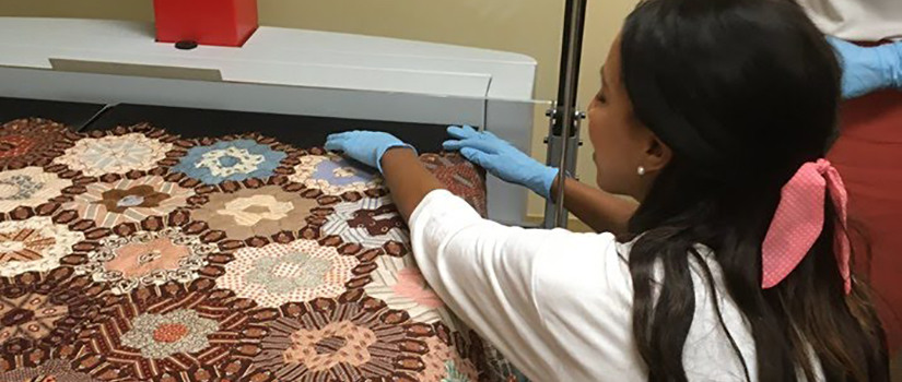 Chauna Carr, a Digital Collections employee, positions an antique quilt onto a large flatbed scanner in preparation for digitally scanning it
