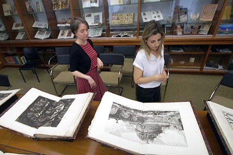 Jeanne Britton and a student looking at several large volumes of Giovanni Piranesi's etchings