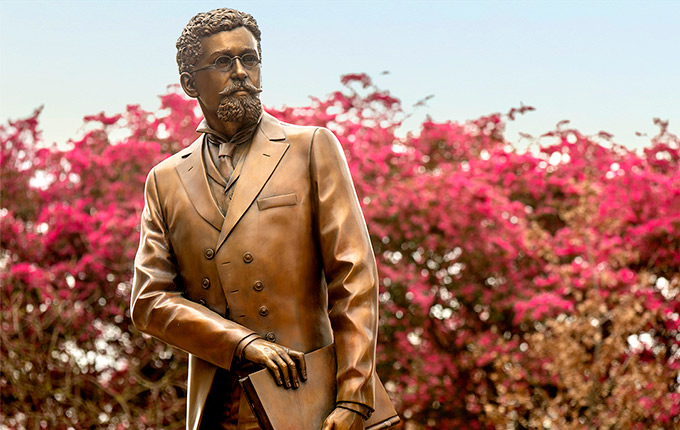 Richard T. Greener Statue with pink flowering trees behind it.