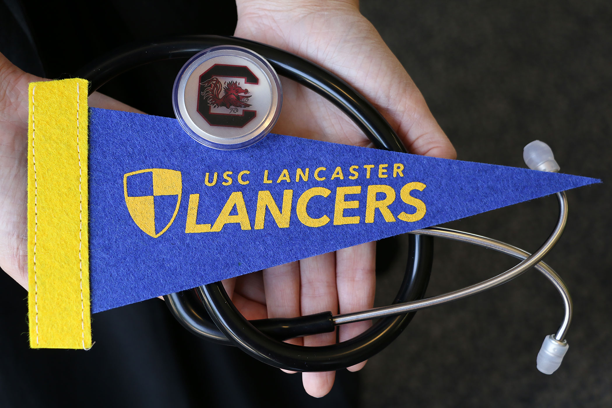 Hands holding a stethoscope and a USCL pennant