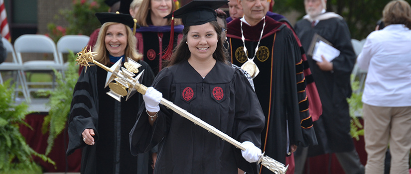 Graduate carries the Carolina Mace during commencement exercises.
