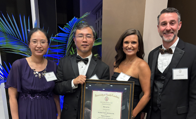 Dr. Lai holds trustee award along side his wife, Dean April Cone and her husband.