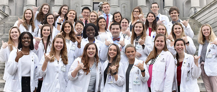 Group of pharmacy students in white lab coats on State House steps