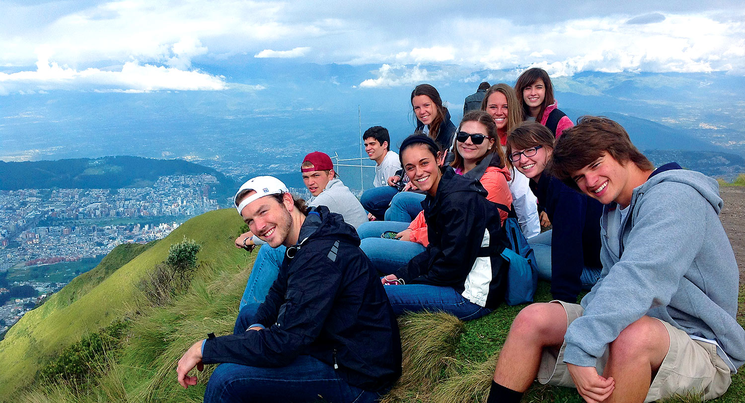 Group of students sitting on a mountain overlooking a city on a study abroad trip.