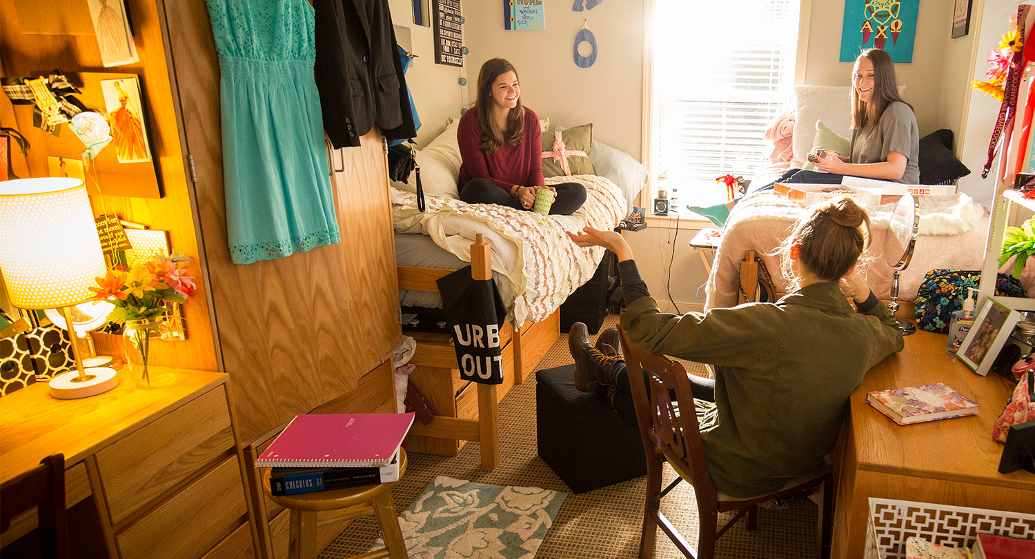 Three students hanging out in a dorm room. 