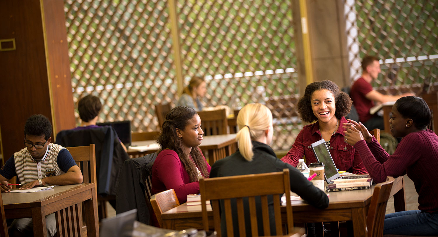Group of students studying together at a table in the library.