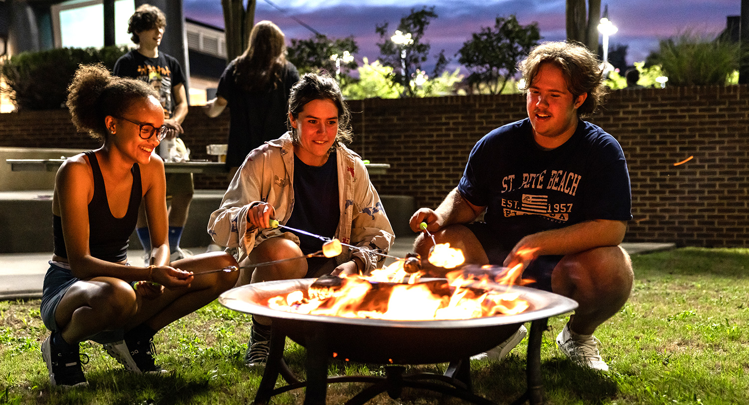 Students toasting marshmallows at a fire pit at RecFlix n' Chilll.