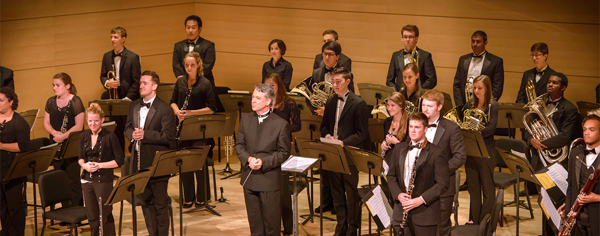 music students in concert band standing for applause at the end of a performance