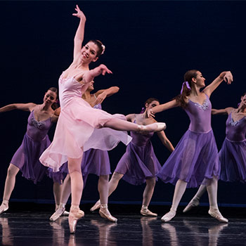 Students in costums and ballet shoes dancing on stage. 
