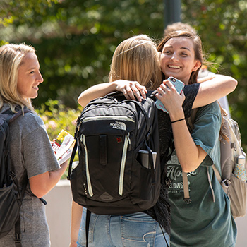 Students greeting each other with a hug on the first day of class. 