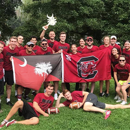 a large alumni group pose outside with South Carolina flags