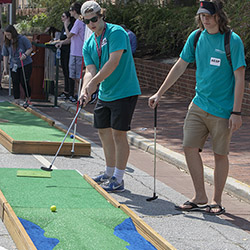 Student playing miniature golf on Greene Street during welcome week