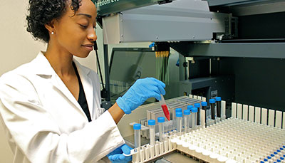 Researcher wearing a lab coat holding a test tube in her hand.