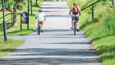 An adult and child riding bikes on a path in a parl.