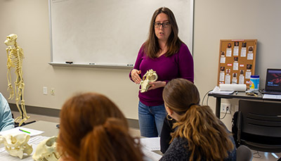 Teacher holding an animal skull in a classroom with students