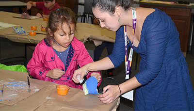 Student teacher working with a young child on an art project.