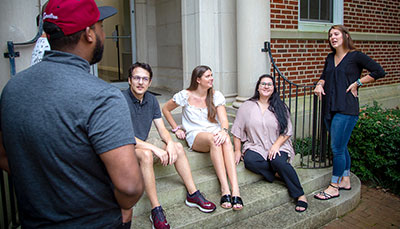 Group of students sitting on the steps of a building outside. 