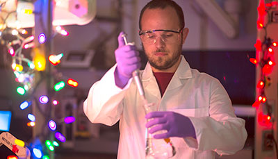 Researcher working in a lab wearing a lab coat holding a pipette. 