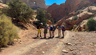 Group of students out in the desert surrounded by large rock formations.