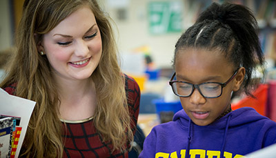 Teacher talking to a student in a classroom setting.