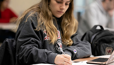 Student in a classroom writing down notes.