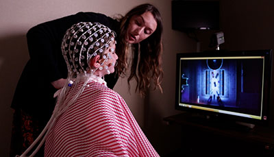 Person examining a patient with an EEG on their head.