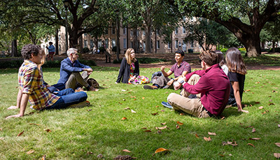 Students and professor sitting in the grass on the horseshoe at USC.