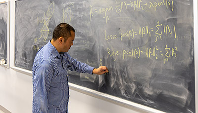 Professor writing equations on a blackboard.