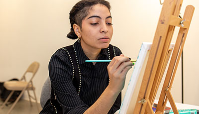 Student painting on a canvas on an easel.