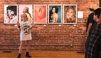 Student standing in front of framed photographs in a gallery.