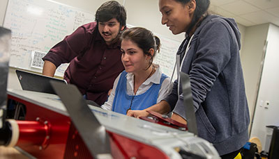 Three students working together looking at a computer.
