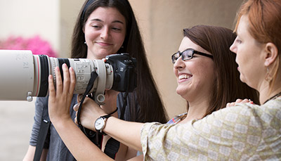 Students viewing dslr camera with telescopic lens