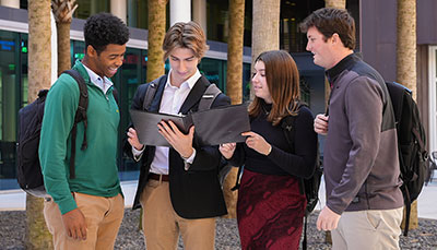 Group of business student standing outside in the Moore School courtyard.