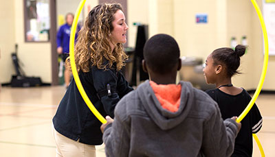 A student teacher working with younger students in a gym. 