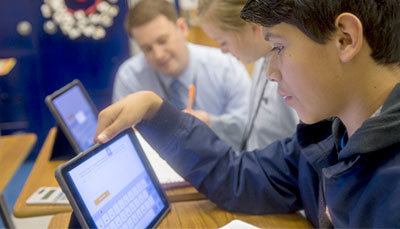 Young student using an iPad in a classroom.