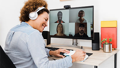 Person sitting a computer with a video conference going on on the screen. 