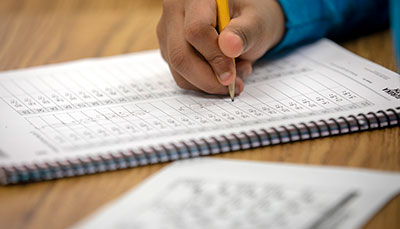 Young student holding a pencil writing in a notebook.