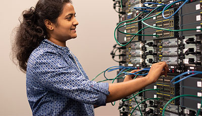 Student working at a wall of servers. 