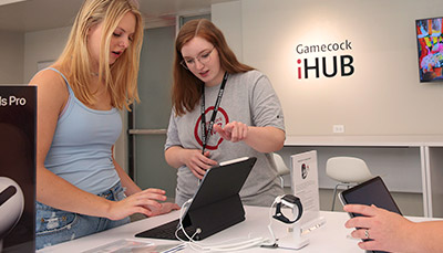 Two people looking over a laptop in the iHub retail showroom. 